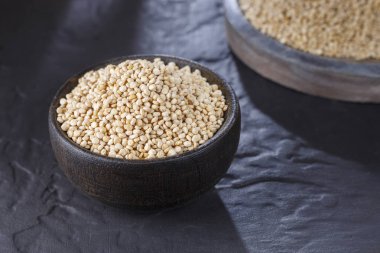 Quinoa Tahıl kaşık ve siyah arka plan üzerine kase