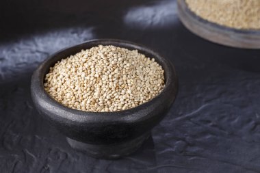 Quinoa Tahıl kaşık ve siyah arka plan üzerine kase