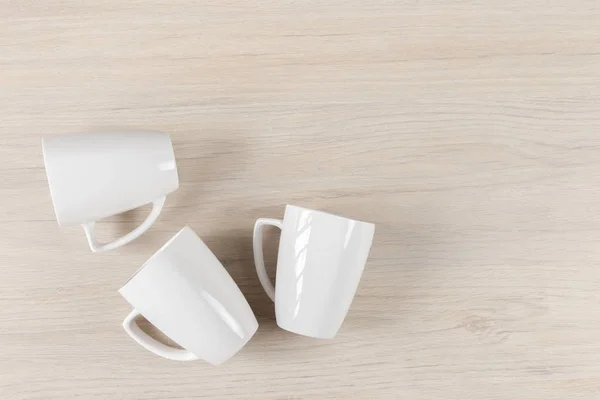 Белые керамические чашки на деревянном фоне, изображение — стоковое фото