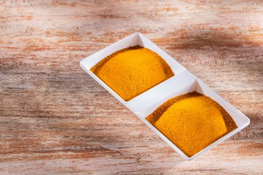 Tahta arka planda kabın içindeki zerdeçal tozu (Curcuma longa)