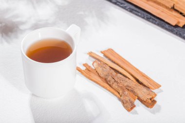 Beyaz arka planda kedi pençesi bitkisi kabuğu ve çayı - uncaria tomentosa