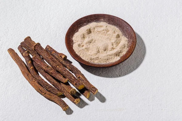 Root and powder of medicinal licorice plant, on white background - Glycyrrhiza glabra