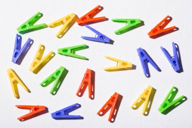 Beyaz arka planda asılı elbiseler için renkli plastik mandallar