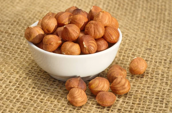 Peeled hazelnuts in a bowl on burlap close-up