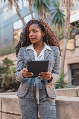 Dijital tablet kullanan Afro-Amerikalı İş kadını şehir ortamında gözlerini kaçırıyor