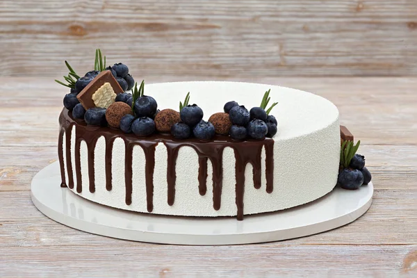 白色慕斯蛋糕装饰浆果和巧克力糖果在一个轻木背景特写视图 — 图库照片