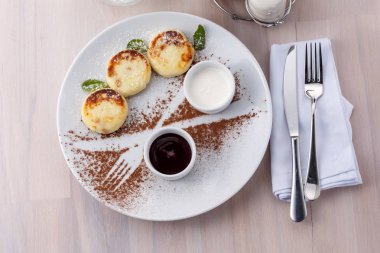 Kuş üzümü reçeli ve ekşi krema ile peynir li krep tabağın üst görünümünde. Düz yatıyordu. Çatal ve bıçak.