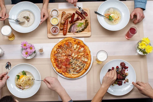 Group of people at the table top view.  Friends or family eating food together. Flat lay.