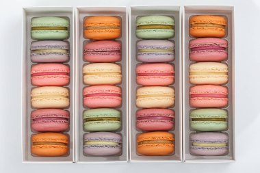 Beyaz arka planda düz kutu ambalaj renkli macaroons yatıyordu