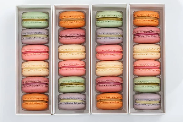 colorful macaroons in packing boxes on white background flat lay