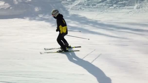 Молодой взрослый лыжник наслаждается идиллической идеальной погодой в холодную зиму. Катание на лыжах в одиночку по идеально ухоженному лыжному трассе на горнолыжном курорте — стоковое видео