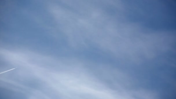 푸른 하늘로 흰 구름을 뚫고 날아가는 비행기. 항공기 뒤에 퍼지고 있는 켐트레일 — 비디오