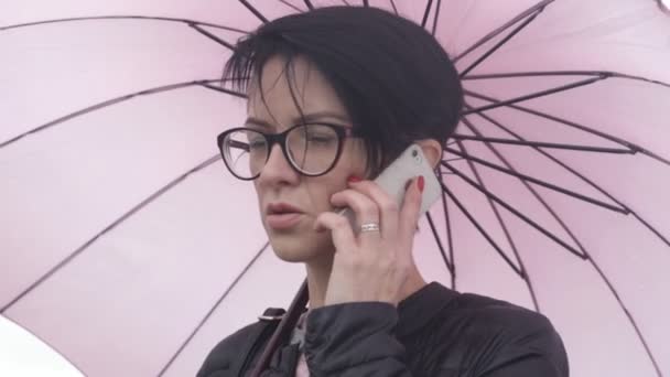 Eine Brillenträgerin Telefoniert Regen — Stockvideo