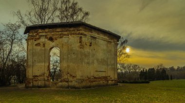 dramatik bulutlu gün batımı gökyüzü arka plan üzerinde akşam şehir Park'ın bahçesinde ilginç antik kalıntılar