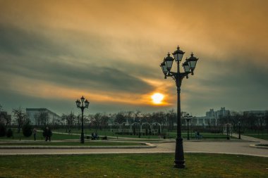 Minsk, Beyaz Rusya - 15 Nisan 2018: sokakları ile bulutlu gökyüzü ve dramatik günbatımı karşı akşam parkta özgün sokak lambaları