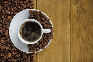 ahşap panoları ve kahve çekirdekleri bir daire arka planı üzerinde beyaz bir fincan kahve. üstten görünüm