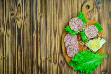 ekmek ve tereyağı, marul ve salam sosis sandviç rendelenmiş peynir kesme tahtası ve ahşap bir zemin üzerine serpilir. Üstten Görünüm