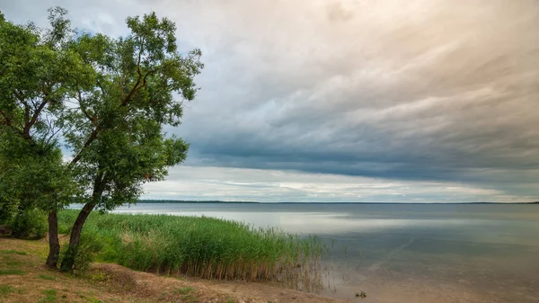 Prachtig uitzicht vanaf de kust naar een groot meer onder een bewolkte hemel voor een onweersbui — Stockfoto