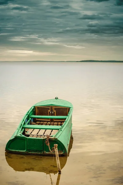 Metalen vissersboot afgemeerd aan de oever van het meer in ondiep water — Stockfoto