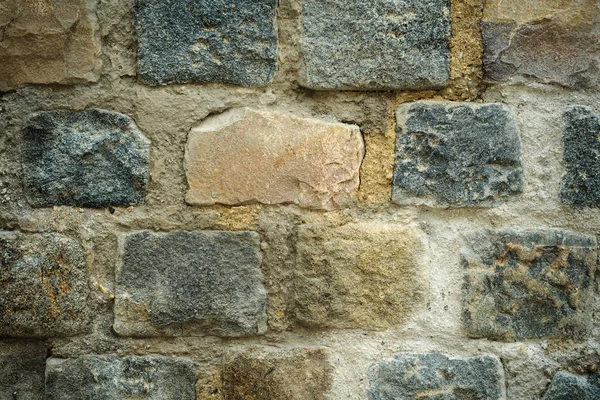 Art background of an old wall with a masonry of multi-colored rectangular granite blocks and cement mortar. close-up — Stock Photo, Image