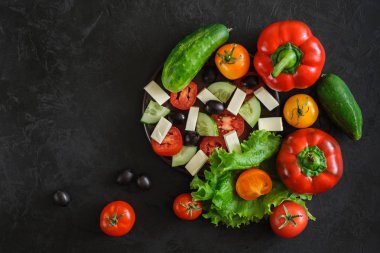 bir yunan salatası bütün ve dilimlenmiş için taze sebze bir dizi üst görünümü ?? siyah beton arka plan üzerinde. metin, logo, slogan veya reklam alanı ile yaratıcı şablon