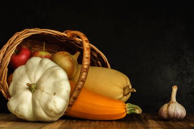 Yalancı bir sepette kabak. Geleneksel sonbahar, siyah beton arka planda sebzelerin sakin yaşamı. Fotokopi uzayı ile sanatsal karanlık kırsal kavram. yan görünüm