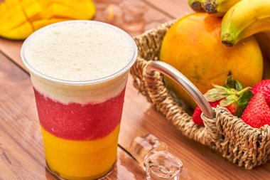 Mango, çilek ve muzlu üç katmanlı tropikal meyve püresi.