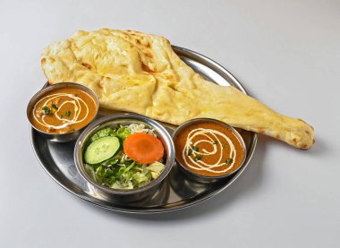 Hint körili menü, Hint ekmeği, körili tavuk, Dal ve Hint kuzenin beyaz arka plan görünümünde metal tali kaplı taze bir salata.