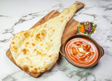 Nan ve salata ile tereyağlı tavuk körisi. Zengin ve kremalı Hint yemeği. Geleneksel bir bakır karahi servis ediliyor.