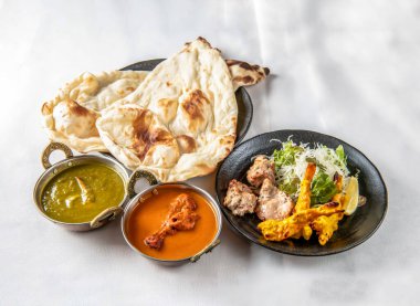 Hint köri seti Saag Curry, Chicken Curry, Naan, Tandoori Chicken ve Chicken Tikka ile beyaz arka planda Hint yemekleri