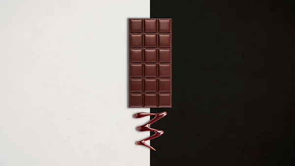 Chocolate bar with melted dark chocolate dripping over black and white background. Confectionery concept backdrop