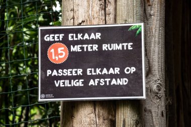 Overloon, Hollanda - 4 Ekim 2020: Sosyal mesafeyi korumak için mağazadan önce dikkat tahtası (Flamanca yazılmış). Sosyal mesafeler, hastalık yayılmasını önlemek için insanlar arasındaki fiziksel mesafeyi kasten artırıyor.