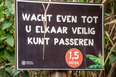 Overloon, Hollanda - 4 Ekim 2020: Sosyal mesafeyi korumak için mağazadan önce dikkat tahtası (Flamanca yazılmış). Sosyal mesafeler, hastalık yayılmasını önlemek için insanlar arasındaki fiziksel mesafeyi kasten artırıyor.