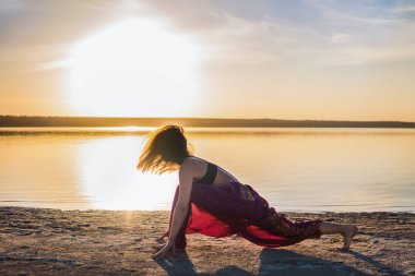 Gün batımında sahilde siluet yoga kadınla.