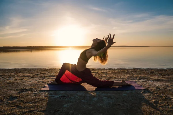 Силует йога жінка на пляжі на заході сонця . — стокове фото