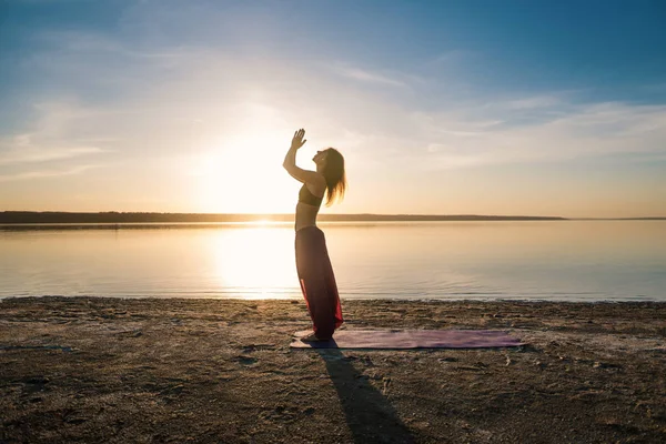 日落海滩上的剪影瑜伽女人. — 图库照片