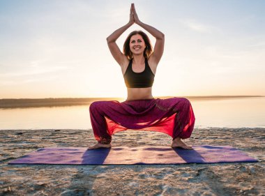 Gün batımında sahilde Yoga kadınla.