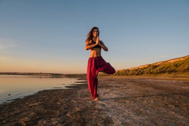 Gün batımında sahilde Yoga kadınla.