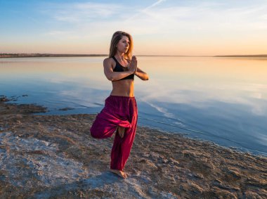 Gün batımında sahilde Yoga kadınla.