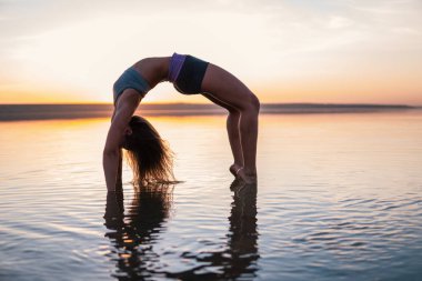 Gün batımında sahilde Yoga kadınla.