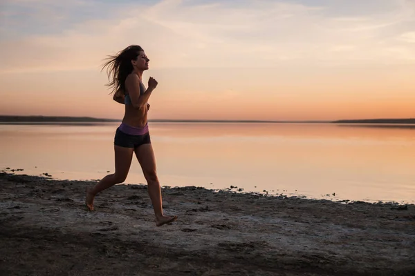 Жінка біжить на пляжі на заході сонця — стокове фото