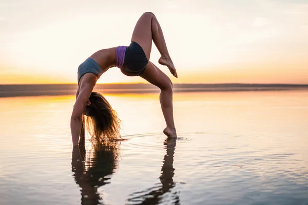 Женщина-йога на пляже на закате . — стоковое фото