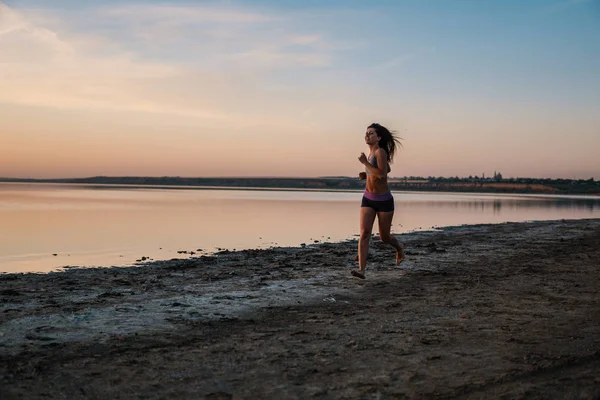 Mujer corriendo en la playa al atardecer — Foto de Stock