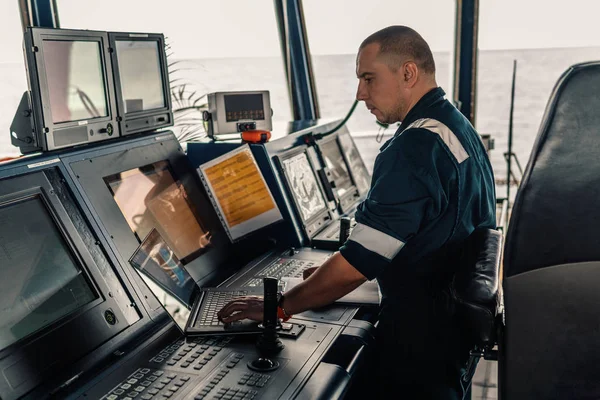 Marine navigational officer is using laptop or notebook at sea