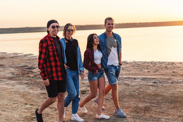 Amigos en la playa juntos caminando al atardecer — Foto de Stock