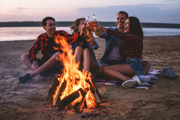 Jóvenes amigos tienen picnic con hoguera en la playa — Foto de Stock