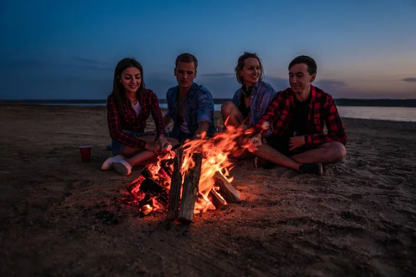 Jóvenes amigos tienen picnic con hoguera en la playa — Foto de Stock