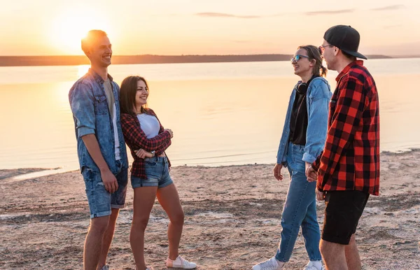 Pareja de amigos en la playa juntos caminando durante la puesta del sol — Foto de Stock