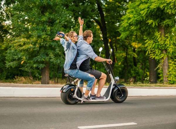 Preciosa pareja joven conduciendo bicicleta eléctrica durante el verano —  Fotos de Stock