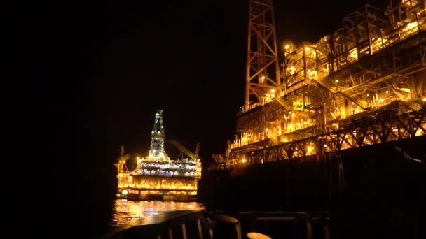FPSO tanker fartyg nära oljeplattform rigg på natten. Offshore olja och gas industrin — Stockvideo
